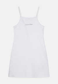Robe fourreau blanche en coton avec de fines bretelles, présentant un design simple et un petit logo gris "Calvin Klein" au dos.