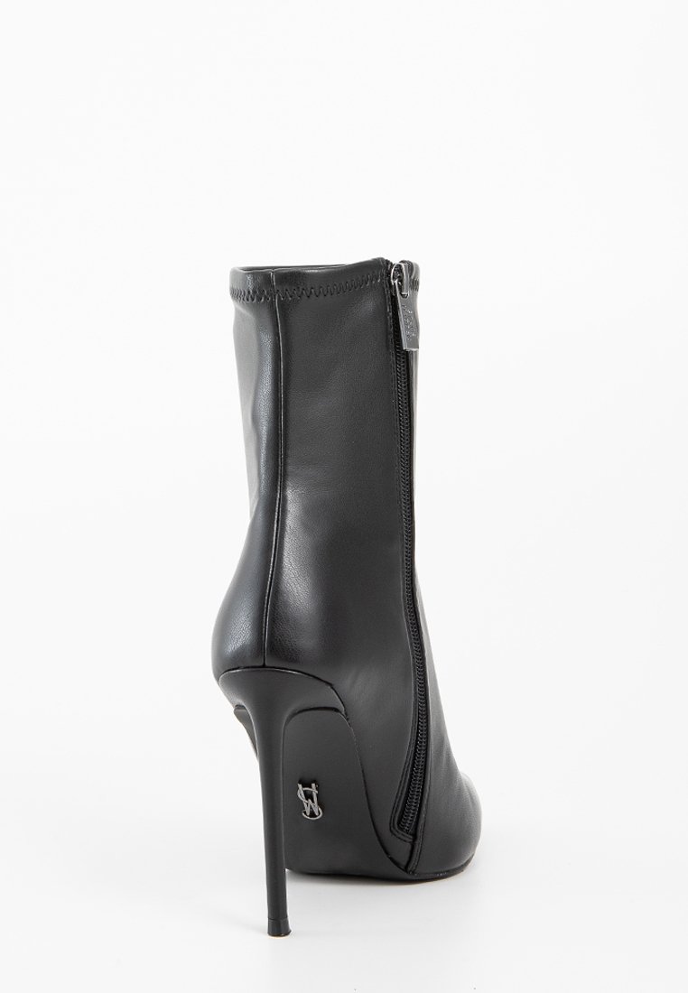 Czarne skórzane botki na wysokim obcasie za kostkę z bocznym zamkiem błyskawicznym, gładka tekstura, zwężający się czubek, elegancka sylwetka i mały detal z logo na obcasie.