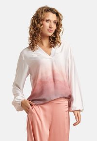 Weiße Satinbluse mit V-Ausschnitt und langen Ärmeln, die einen Farbverlauf von hellrosa zu dunkelrosa am Saum zeigt. Glatte Textur, lockere Passform.