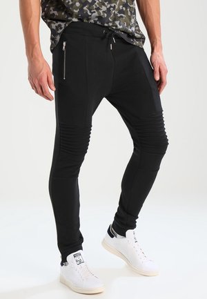 Zwarte joggingbroek met geribbelde knie-accenten, zijritszakken en een taps toelopende pasvorm. Gemaakt van zachte stof voor comfort en flexibiliteit.