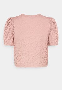 Blouse à manches courtes en dentelle rose pâle avec un motif floral et des manches légèrement bouffantes, vue de dos.