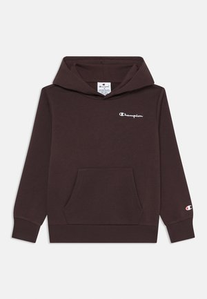 Lila kapucnis pulóver, elülső zsebből és fehér "Champion" logóból áll. Puha, textúrált anyagból készült, bordás mandzsettákkal.