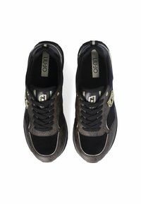 Baskets noires avec des accents marron à motifs, dotées d'une tige texturée, d'une fermeture à lacets et de détails métalliques sur les côtés.