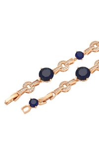 Bracciale tono oro con gemme blu navy alternate a cristalli trasparenti, collegati da elementi di catena decorativi. Design con chiusura sicura.