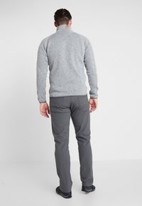 Grå fleecetröja med hög krage, ihop med mörkgrå byxor. Tyget har en texturerad finish och en standard passform.