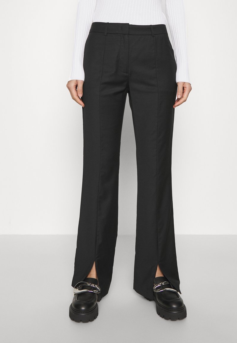 Pantalon noir sur mesure avec coupe droite, présentant des fentes latérales à l'ourlet. Fabriqué en tissu lisse, conçu avec une ceinture classique.