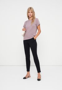 Lyse lilla kortermet t-skjorte kombinert med svarte slim-fit bukser og to-toners flate sko, med en rund hals og subtile sidesømmer.