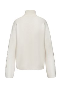 Crème coltrui met een relaxte pasvorm, voorzien van geribde manchetten en zoom, en bold tekst op de rechtermouw in een contrasterend lichtbruin.