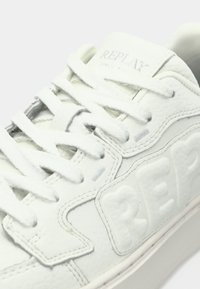 Witte leren sneaker met een getextureerd oppervlak, geperst "REPLAY"-logo, platte veters en rubberen zool. Strak ontwerp met subtiele stikdetails.