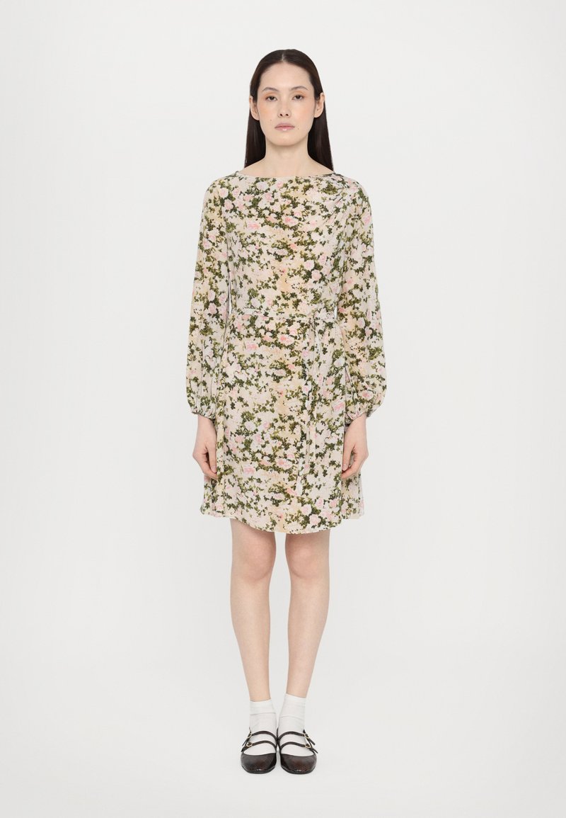 Floral dress in light beige with pink and green patterns, long puff sleeves, a cinched waist, and a hemline above the knee. Worn with dark shoes and white socks.