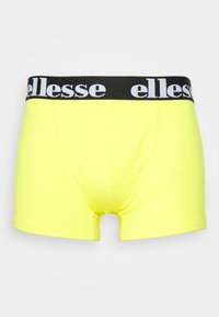Dzeltenas kokvilnas bokseršorti ar melnu elastīgu jostasvietu, uz kuras ir balta "ellesse" zīmola apdruka. Dizains ietver ciešu piegriezumu un gludu tekstūru.