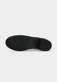 Semelle de chaussure noire avec un motif de bande de roulement profond, montrant la marque "GEOX" et la taille, isolée sur un fond blanc uni.