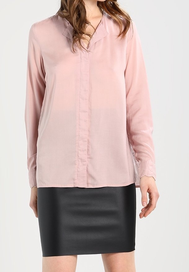 Rosa Bluse mit langen Ärmeln, Knopfleiste und V-Ausschnitt, kombiniert mit einem schwarzen, figurnahen, strukturierten Rock.