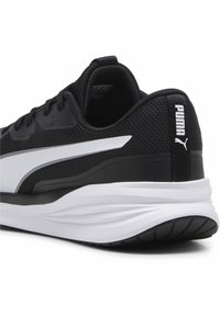 Zwarte sportieve schoen met een gestructureerde mesh bovenkant, witte zijstreep en een gewatteerde witte tussenzool. Heeft een Puma-logo op de hiel.
