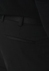 Czarne spodnie o gładkiej fakturze, dopasowanym kroju i jednej kieszeni z delikatnym detalem na plecach.