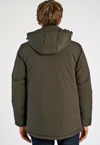 Olivengrøn pufferjakke med hætte, der har en glat tekstur, elastiske manchetter og en lidt længere bagkant.