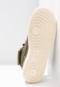 Sole Nike tenisky v olivově zelené barvě s texturovaným gumovým povrchem. Obsahuje kruhové vzory a výrazný dezén podrážky.