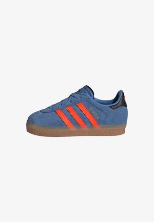 Baskets Adidas Gazelle en daim bleu avec des bandes orange et une semelle en gomme, vue de côté sur fond blanc.