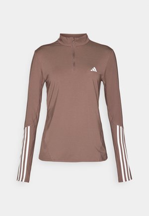 Maglietta atletica a maniche lunghe marrone con zip a metà, caratterizzata da accenti bianchi a tre strisce sulle maniche e un piccolo logo bianco sul petto.