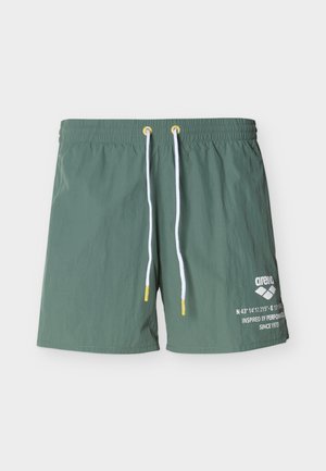 Zielone kąpielówki z lekkiego materiału, z sznurkiem w żółtych akcentach i białym logo/szczegółami z przodu.