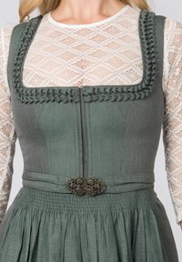 Graues Kleid mit eng anliegendem Oberteil und ausgestelltem Rock. Verfügt über eine dekorative geflochtene Borte, einen Reißverschluss und eine brosche mit Blumenmuster.