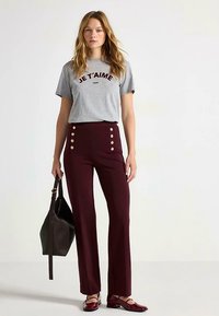 Grå bomulds-T-shirt med "JE T'AIME PARIS" tryk, kombineret med bourgognefarvede bukser med høj talje, der har guldknapper og en udvidet pasform.