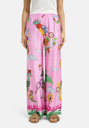 Loose pink pants with colorful fantasy birds, flowers, clouds, and sun designs worn with a white ribbed tank and tan sandals.