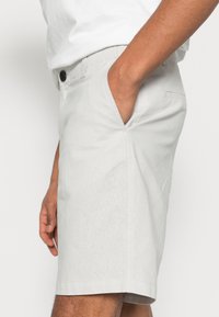 Lichtgrijze shorts van gestructureerde stof met een rechte snit. Voorzien van zijzakken en een knoopsluiting. Minimalistisch ontwerp.