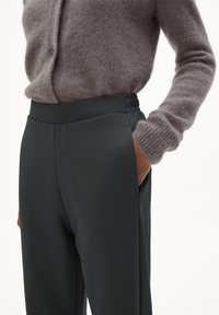 Donkergrijze op maat gemaakte broek met een gladde textuur, elastische tailleband en zijzakken, gecombineerd met een lichtgrijze pluizige gebreide trui.