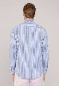 Camicia a righe blu e bianche con maniche lunghe, colletto standard e polsini con bottoni. Tessuto morbido e orlo arrotondato.