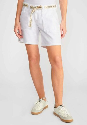 Witte katoenen shorts met een trekkoord in de taille, versierd met een patroon op het lint. Gecombineerd met lichtgekleurde sneakers. Eenvoudig en functioneel ontwerp.