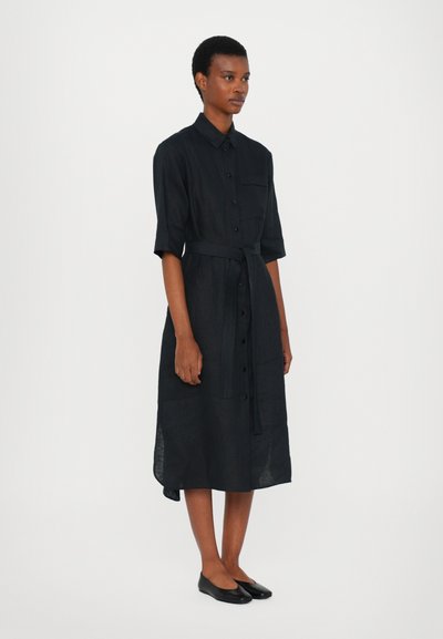Vestido de linho preto com mangas curtas, frente de botões, bolsos laterais e um cinto à match, apresentando um corte relaxado e um design até aos joelhos.