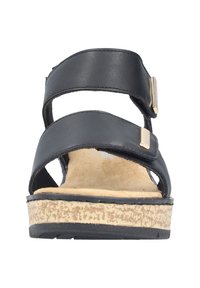 Sort åben tå-sandal med to brede remme og gyldne rektangulære detaljer, polstret beige fodseng og tekstureret beige korklignende sål.