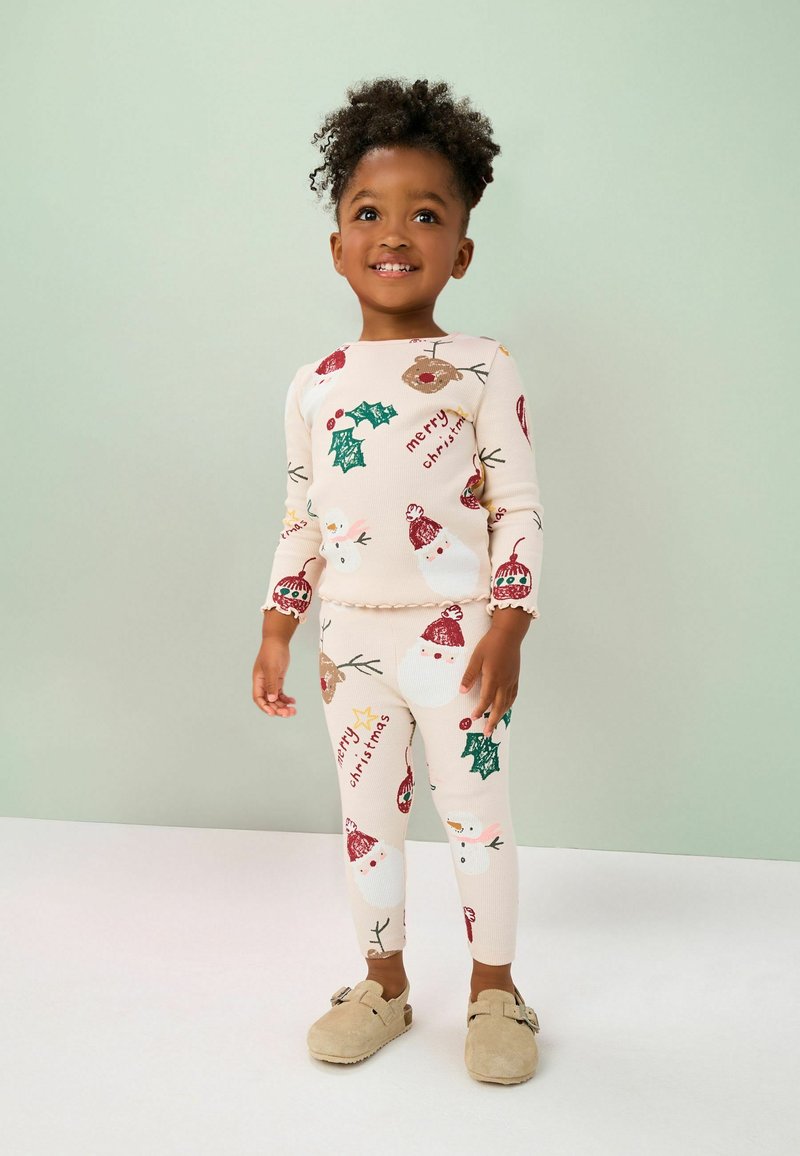 Pyjamas crème comprenant des motifs festifs de bonhommes de neige, de houx et de messages de Noël. Tissu doux et extensible avec une texture côtelée.