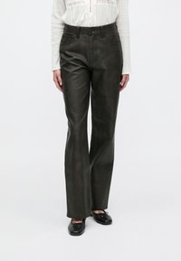 Dark green leather flared pants with a mid-rise waist, five-pocket design, and subtle sheen; paired with black flat shoes.