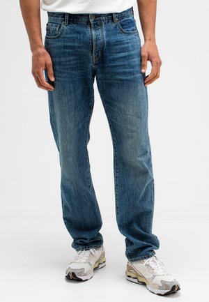 Lichtblauwe denim jeans met een relaxte pasvorm, vijf-pocket ontwerp en subtiele vervaging. Gecombineerd met witte en grijze sneakers.