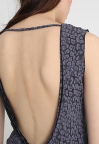 Sleeveless gray top with a low back, featuring a textured leopard print pattern and contrast stitching along the edges.