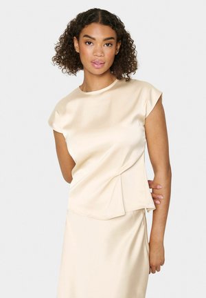 Cream satin top with short sleeves, round neckline, and asymmetrical pleat detail at the waist, paired with a smooth skirt.