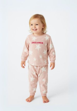 Pyjamas en polaire rose doux avec des motifs d'étoiles blanches, un top à col rond avec le texte "DREAMER", et un pantalon assorti avec des poignets.