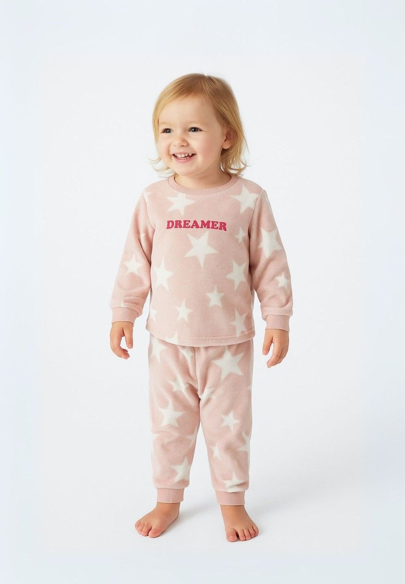 Pyjamas en polaire rose doux avec des motifs d'étoiles blanches, un top à col rond avec le texte "DREAMER", et un pantalon assorti avec des poignets.