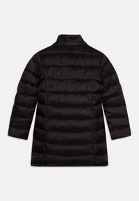 Svart puffjacka med rak silhuett. Har horisontell sömnad, ståkrage och långa ärmar. Lätt och isolerande tyg.