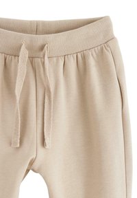 Beige sweatpants har en ribbet talje med snore og sidelommer. Stoffet ser blødt og struktureret ud, velegnet til afslappet brug.