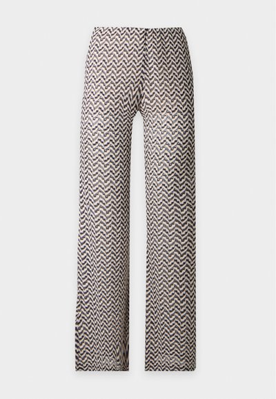 Pantalon à jambes larges avec un motif zigzag en noir, beige et blanc sur un fond clair.