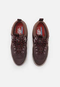 Bruna sneakers med en texturerad ovandel, grå gummisula och livliga orange snören. Har vadderad krage och "UltraCush"-logotyp inuti.