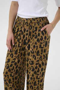Pantalons larges en imprimé léopard marron et noir, présentant une taille élastique, des poches et un tissu texturé.