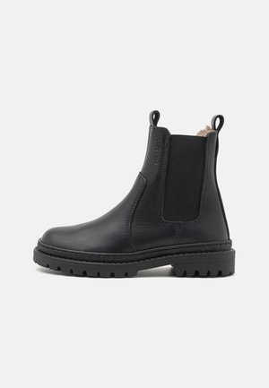 Bottine noire en cuir avec panneaux latéraux élastiques, languettes à l'avant et à l'arrière, semelle robuste et doublure intérieure douce visible.