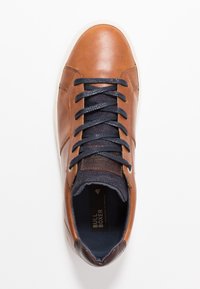 Braune Ledersneaker mit marineblauen Stoffakzenten, runder Spitze und strukturiertem Obermaterial. Mit blauen Schnürsenkeln und einer weißen Gummisohle. Markenlabel sichtbar.