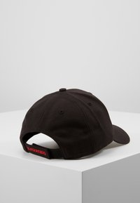 Black baseball cap made of fabric with a curved brim, adjustable strap at the back featuring a red text detail, smooth texture.