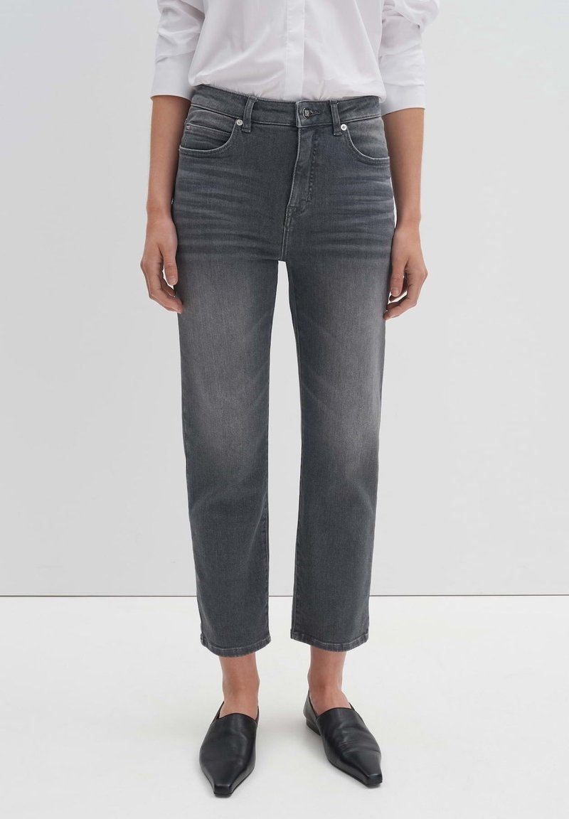 Jeans grigi alti in vita con taglio dritto, design a cinque tasche e leggera scoloritura. Abbinati a scarpe nere senza lacci.