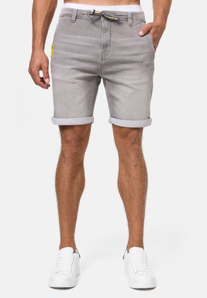 Shorts en denim gris avec ourlets retroussés, dotés d'une taille à cordon de serrage et de poches latérales. Associés à des baskets blanches.
